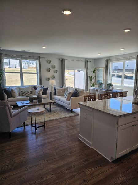 A bright living area with cozy sofas, a chic coffee table, and a spacious kitchen island under recessed lighting. A bright living area with cozy sofas, a chic coffee table, and a spacious kitchen island under recessed lighting.