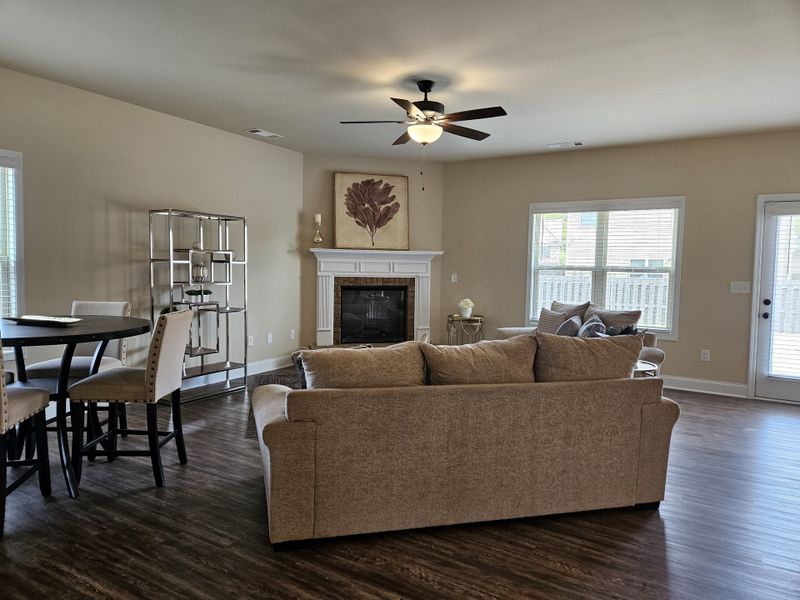 A cozy living room featuring a plush sofa, modern dining area, and elegant fireplace with natural light streaming in. A cozy living room featuring a plush sofa, modern dining area, and elegant fireplace with natural light streaming in.