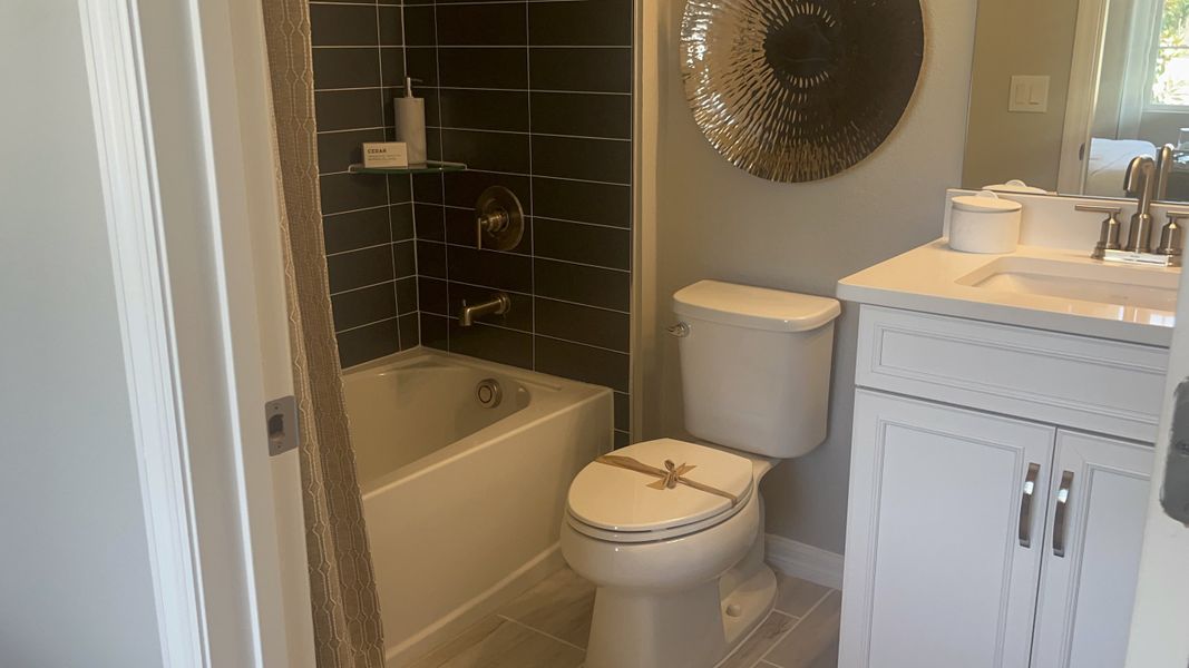 A modern bathroom featuring sleek black tiles, a white vanity, and stylish fixtures.