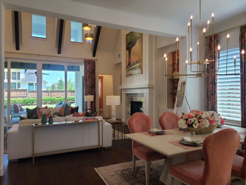 A bright living room with vaulted ceilings, elegant chandelier, and a cozy dining area adorned with pink velvet chairs. A bright living room with vaulted ceilings, elegant chandelier, and a cozy dining area adorned with pink velvet chairs.