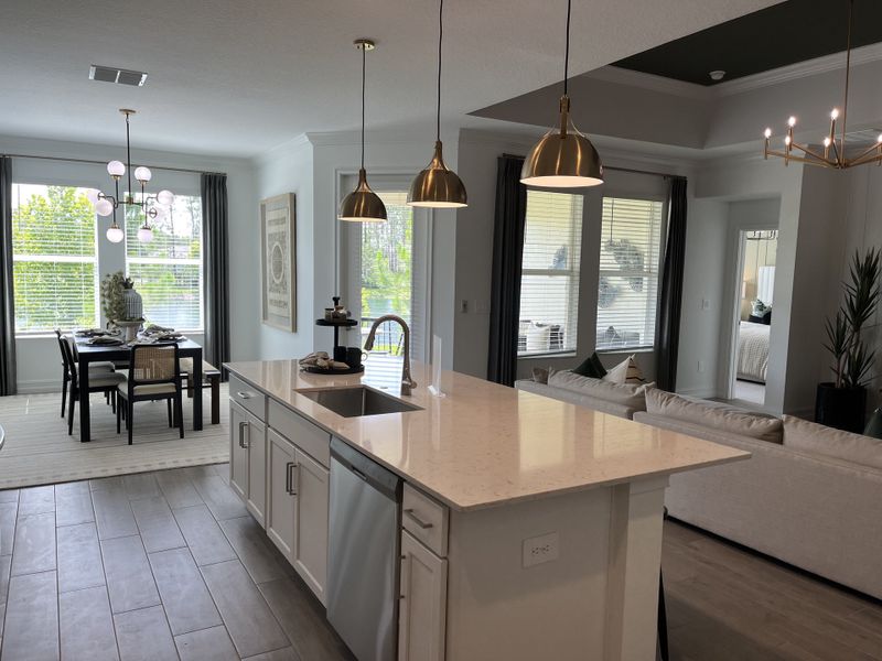 A contemporary open-plan kitchen and dining area featuring stylish pendant lights, a sleek island, and ample natural light.