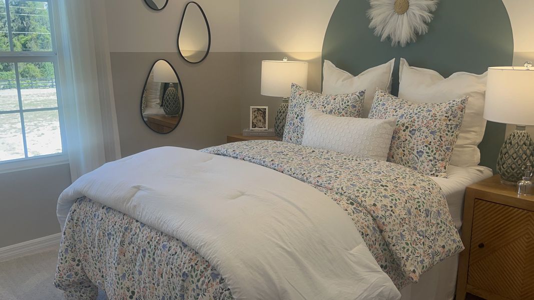 A cozy bedroom with floral bedding, elegant mirrors, and soft lighting creates a relaxing atmosphere.