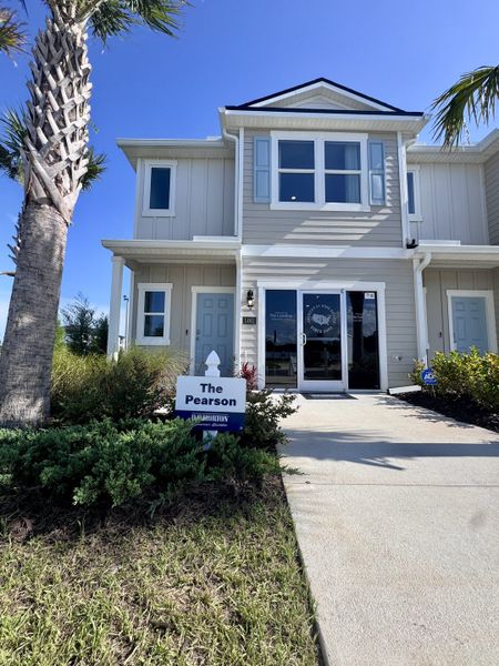 A modern two-story gray home with manicured shrubs in The Landing by D.R. Horton (Middleburg, FL).