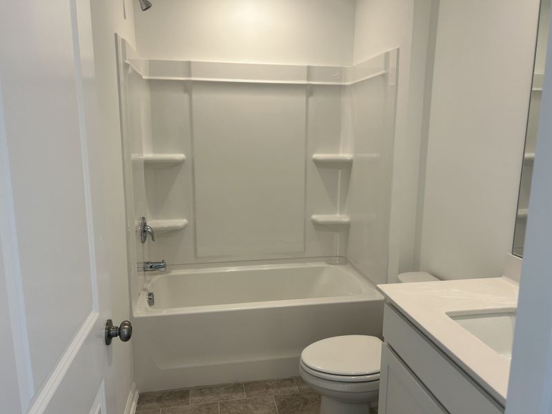 A modern bathroom featuring a dual vanity and elegant marble-style tiled shower in Sherri Downs by Lennar (Angier, NC).