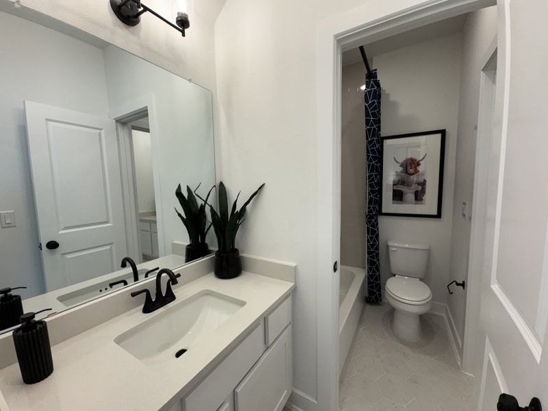 A modern bathroom with white cabinetry, a sleek black faucet, and a stylish geometric shower curtain.