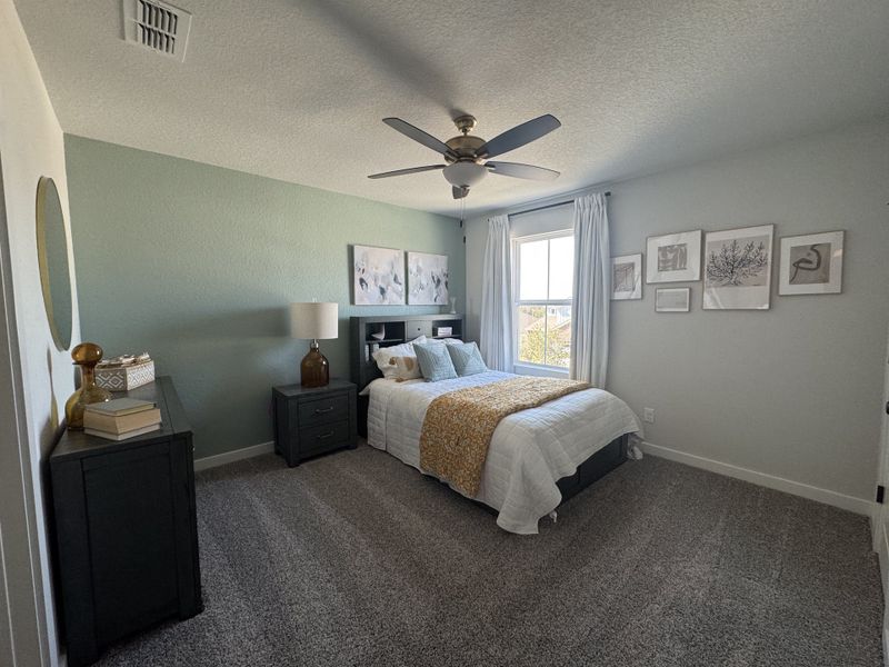 A cozy bedroom with soft green accents, gray carpet, modern decor, and abundant natural light. A cozy bedroom with soft green accents, gray carpet, modern decor, and abundant natural light.