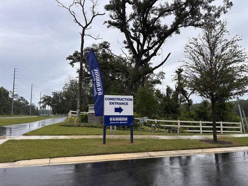 A rainy entrance to new homes in Wynwood by D.R. Horton, surrounded by lush greenery in Ocoee, FL.