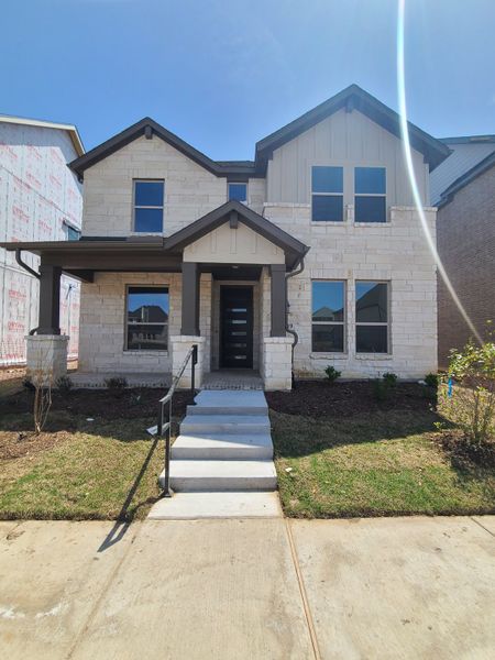 A modern stone-accented home with a cozy porch in Cross Creek Meadows 60s by Taylor Morrison (Celina, TX).