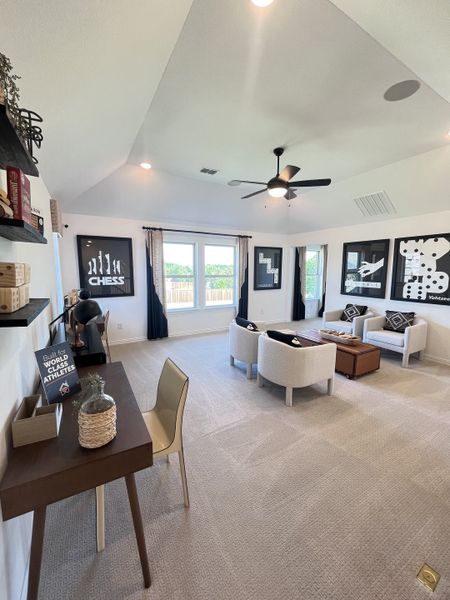 A cozy, contemporary living space with neutral tones, a stylish ceiling fan, and chic wall art, perfect for relaxation.