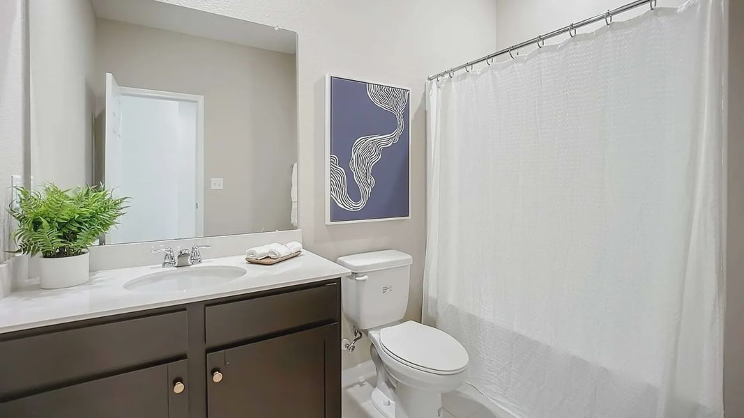 Sophisticated bathroom features sleek dark cabinetry and elegant white accents in Panther Creek.