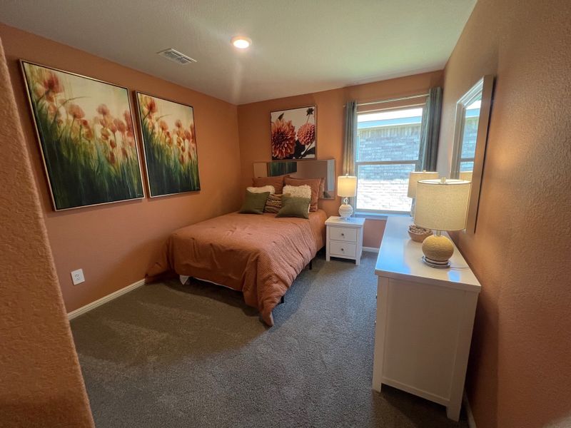 A cozy bedroom with warm earthy walls, vibrant floral artwork, a comfy bed, and modern lamps on sleek white furniture. A cozy bedroom with warm earthy walls, vibrant floral artwork, a comfy bed, and modern lamps on sleek white furniture.