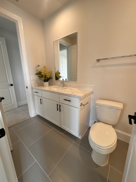 A modern bathroom with a sleek vanity, large mirror, white cabinets, and neutral tiles, creating a clean and inviting space.