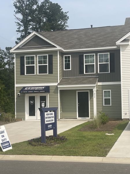 A charming green and gray townhome with a pristine lawn in Carolina Groves Townhomes by D.R. Horton (Moncks Corner, SC).