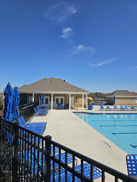 A vibrant community pool with blue loungers and umbrellas in Braselton Village by D.R. Horton (Braselton, GA).