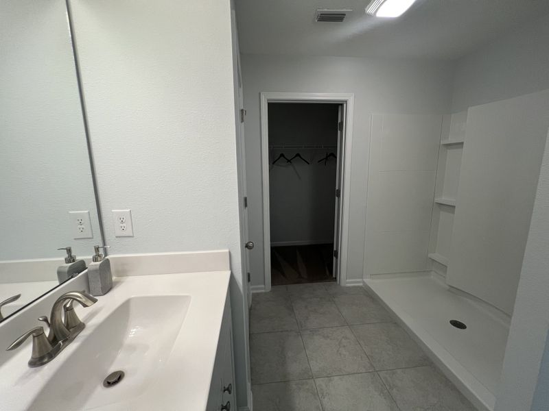 A sleek bathroom with a large mirror, modern faucet, spacious shower, and tiled flooring. A sleek bathroom with a large mirror, modern faucet, spacious shower, and tiled flooring.