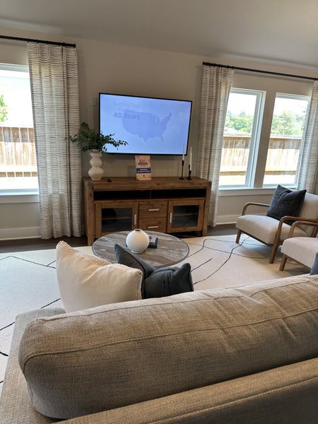A cozy living room with modern decor, neutral tones, a large TV, and stylish curtains, perfect for relaxing or entertaining. A cozy living room with modern decor, neutral tones, a large TV, and stylish curtains, perfect for relaxing or entertaining.