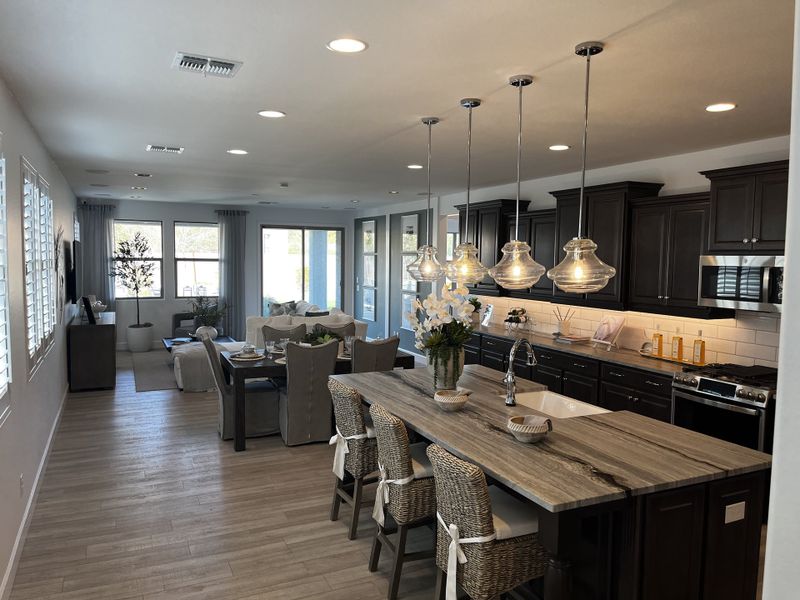 A modern kitchen with dark cabinetry, pendant lighting, and a central island with seating.