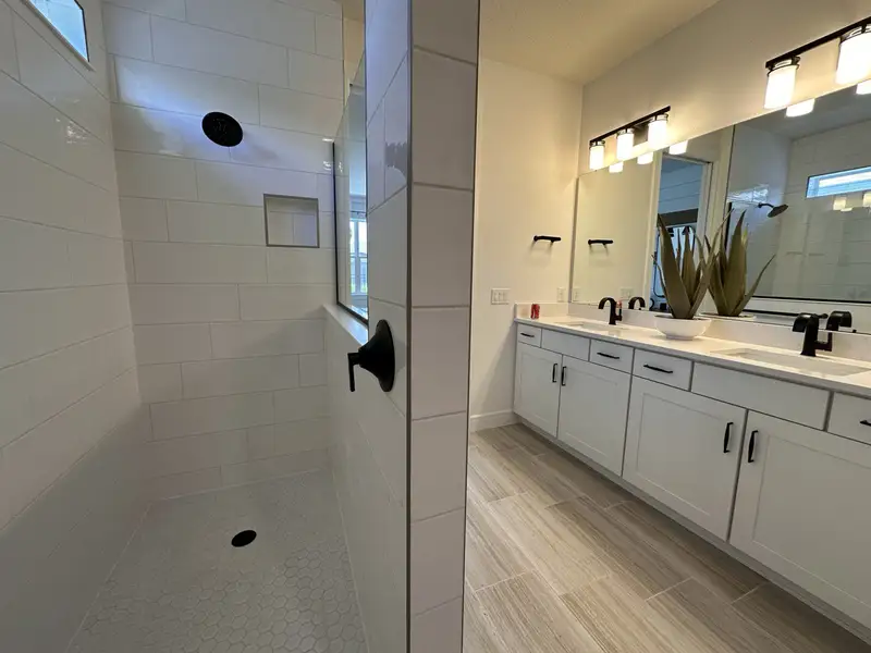 A modern bathroom featuring a spacious shower, dual vanity with sleek fixtures, and sophisticated lighting.
