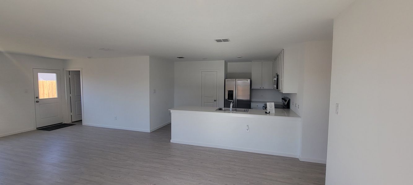 A bright, open-concept living space with light wood floors and a modern kitchen featuring stainless steel appliances. A bright, open-concept living space with light wood floors and a modern kitchen featuring stainless steel appliances.