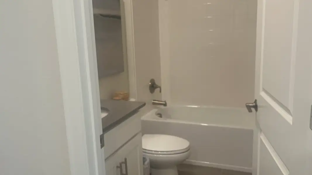 A cozy bathroom with a sleek vanity, modern fixtures, and a clean white bathtub.