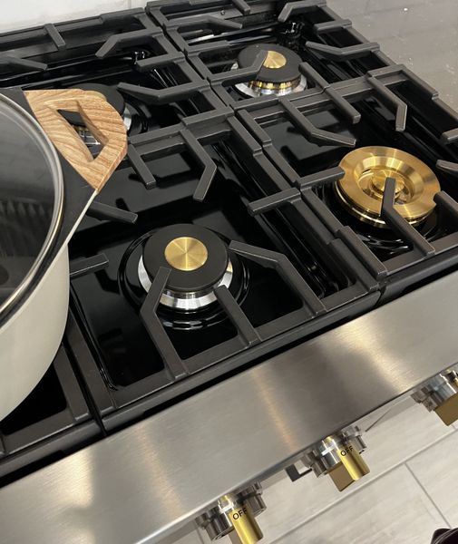 A sleek stainless steel gas cooktop with elegant brass accents and a modern design, perfect for gourmet cooking. A sleek stainless steel gas cooktop with elegant brass accents and a modern design, perfect for gourmet cooking.