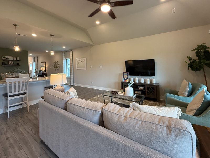 A cozy living area with a plush sectional, modern decor, open kitchen, and warm lighting creating an inviting ambiance.