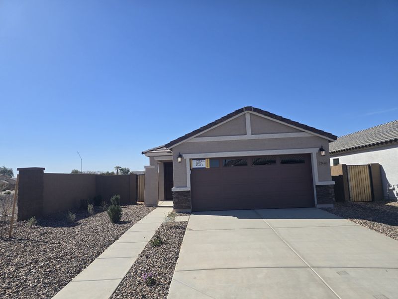 A modern single-story home with a stone-accented exterior and tidy landscaping in Anderson Farms: Premier by Lennar (Maricopa, AZ).