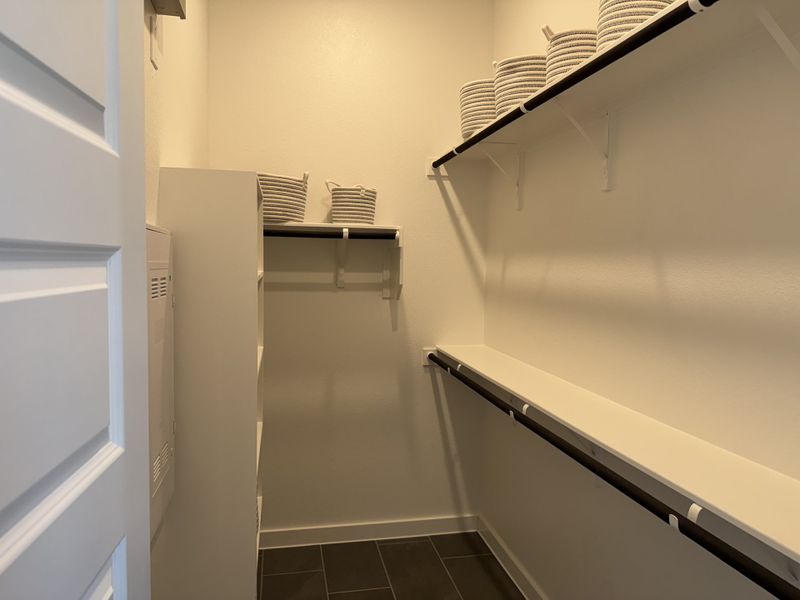 A tidy laundry room with organized shelving and striped baskets for storage.