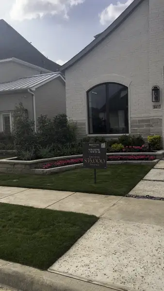 A charming light brick home with lush landscaping in The Tribute 50' by Britton Homes (Frisco, TX).