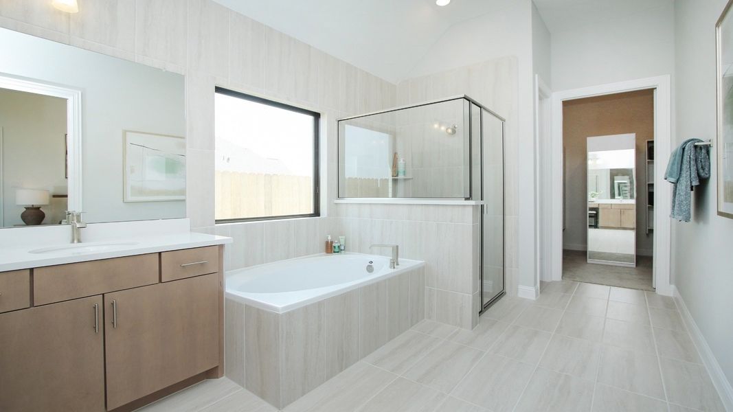 Indulge in the Sunterra community’s luxurious bathroom with a sleek glass shower and refined wood cabinetry.