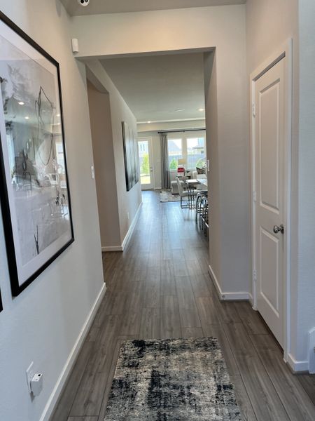 A welcoming hallway with sleek wood flooring, modern art, and a view into a bright living room space.