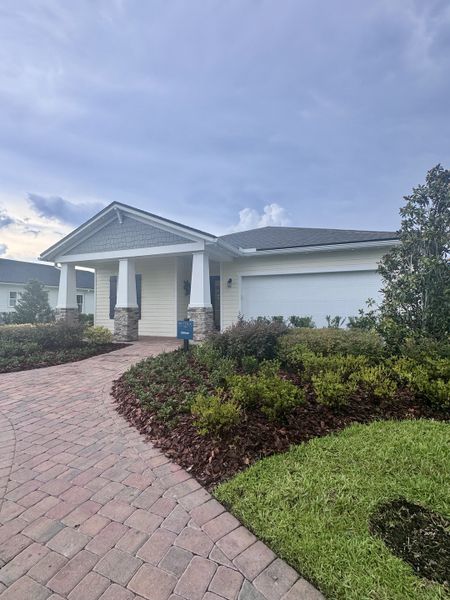 Charming white home with a welcoming porch and lush landscaping in Reverie at TrailMark by Dream Finders Homes (St. Augustine, FL).