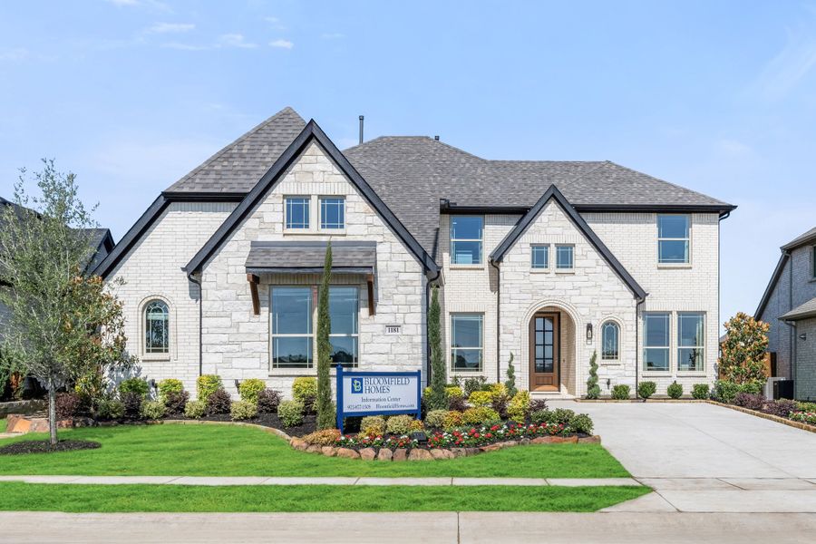 Bloomfield Homes two-story model home with white brick and stone exterior, arched entry, and landscaped front yard Bloomfield Homes two-story model home with white brick and stone exterior, arched entry, and landscaped front yard