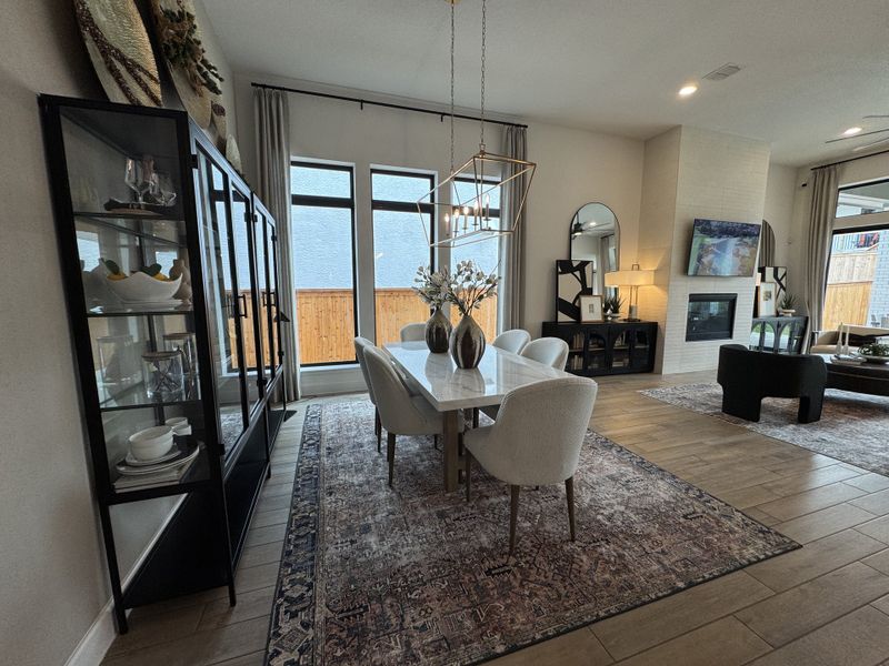 A sophisticated living and dining space with large windows, elegant decor, and a cozy fireplace.