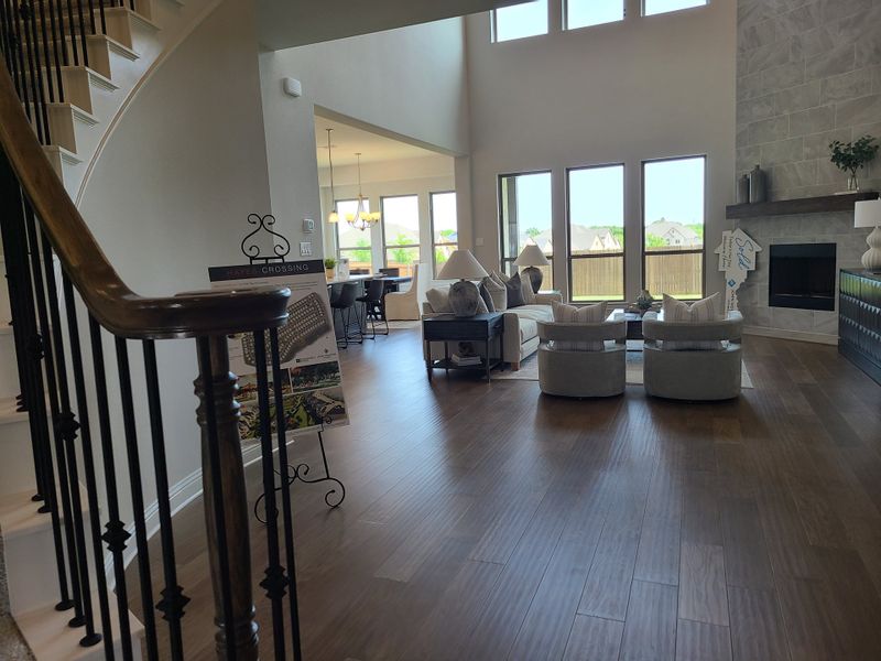 A bright, open living area with sleek wood floors, large windows, and a cozy seating arrangement by the fireplace.