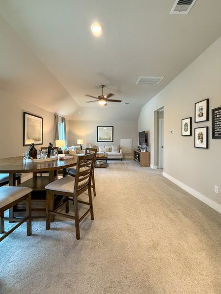 A spacious living area with plush carpeting, elegant dining table, cozy seating, and contemporary decor.