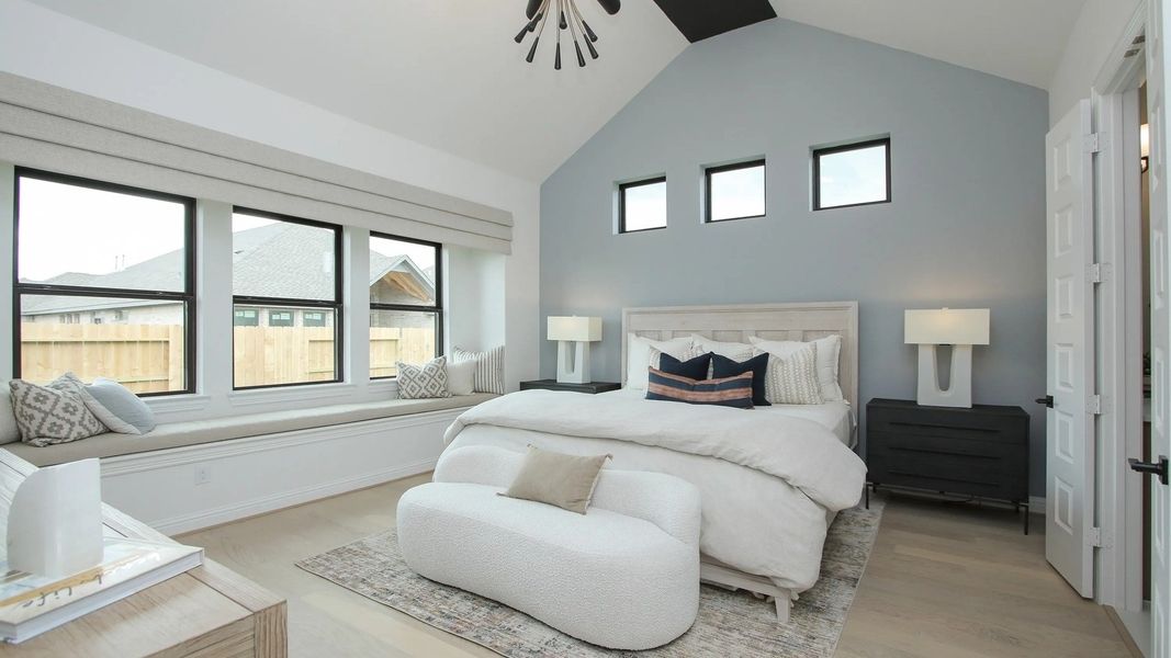 Vaulted ceiling, chic lighting, and expansive windows define this luxury Coastal Point bedroom. Exclusive living space.