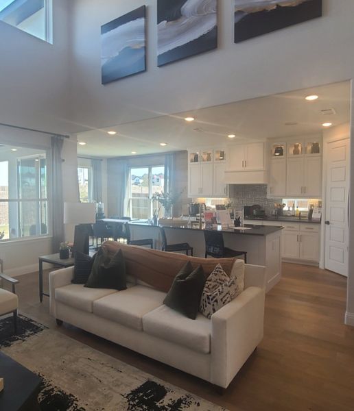 A modern open-concept living area featuring a cozy sofa, elegant kitchen, and large windows for natural light.