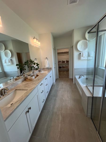 A sleek bathroom with double vanity, spacious mirrors, and a glass-enclosed shower.
