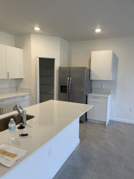 A sleek kitchen featuring a spacious island with a built-in sink, modern white cabinetry, and stainless steel appliances.