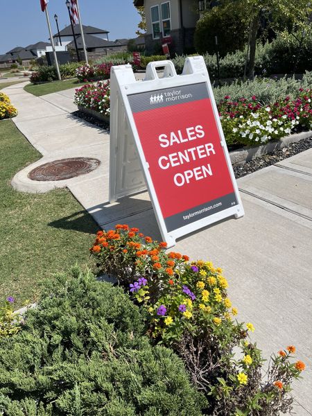 Sales center open at Bridge Creek 45s and 50s by Taylor Morrison in Cypress, TX, with vibrant landscaping and flowers.