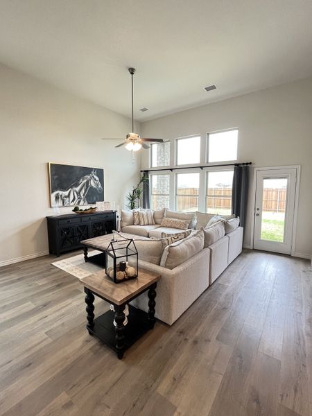 A spacious living room with large windows, a cozy sectional sofa, and modern decor featuring light wood flooring.