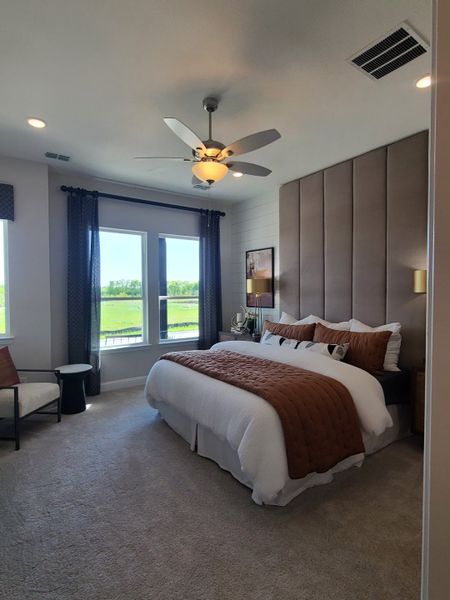 A cozy bedroom featuring a plush bed, elegant headboard, and lots of natural light with scenic views.