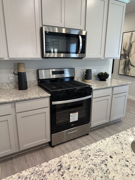 A modern kitchen featuring sleek white cabinetry, stainless steel appliances, and elegant granite countertops.