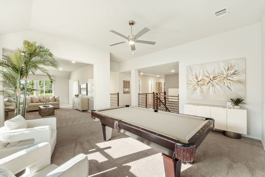 Spacious game room with pool table, ceiling fan, carpet flooring, and open layout connecting to living area.