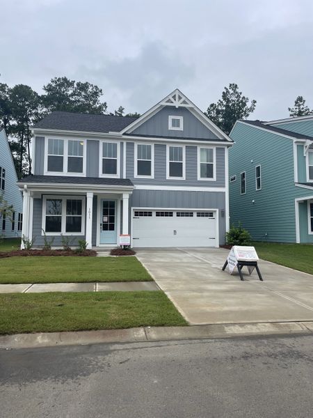 Charming gray two-story home with a manicured lawn in Homecoming by True Homes (Ravenel, SC).