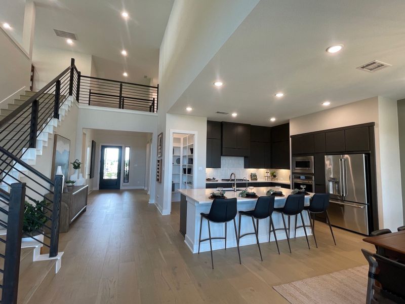 An elegant open-plan kitchen with sleek black cabinets, a spacious island, and contemporary lighting. Perfect for modern living. An elegant open-plan kitchen with sleek black cabinets, a spacious island, and contemporary lighting. Perfect for modern living.