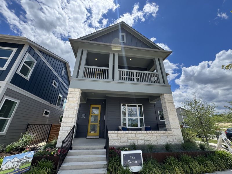 A modern two-story home with stylish stone accents and vibrant landscaping in The Twilight at Goodnight Ranch by David Weekley Homes (Austin, TX).