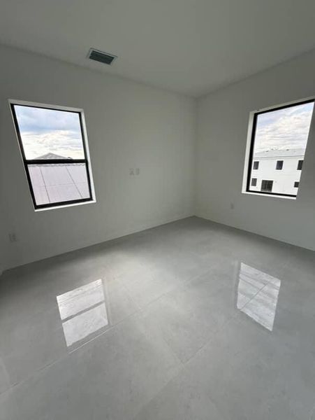 A bright, minimalist room with glossy tiled floors and large windows.