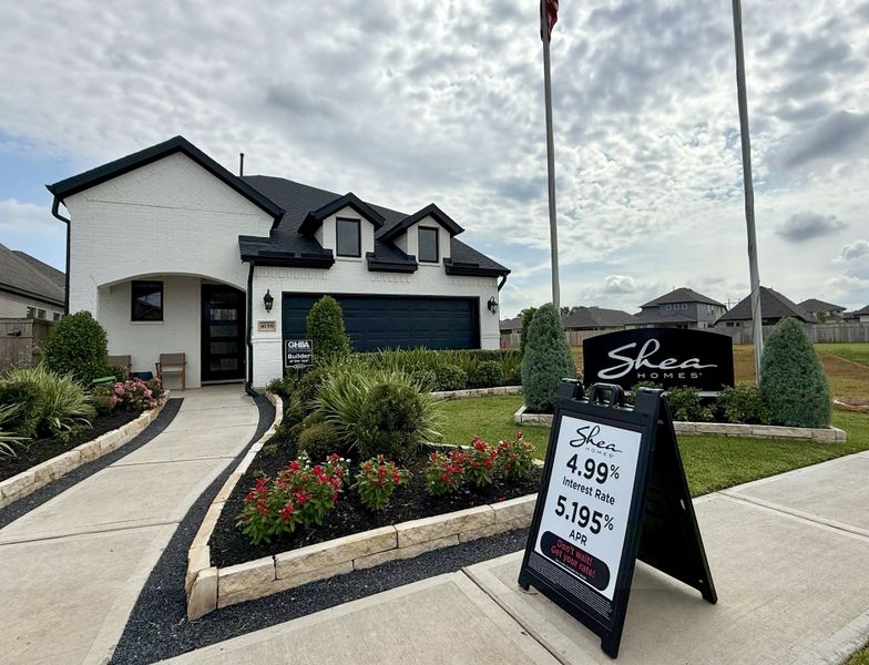 A charming white brick home with dark accents and lush landscaping in Sienna 65' by Shea Homes (Missouri City, TX).